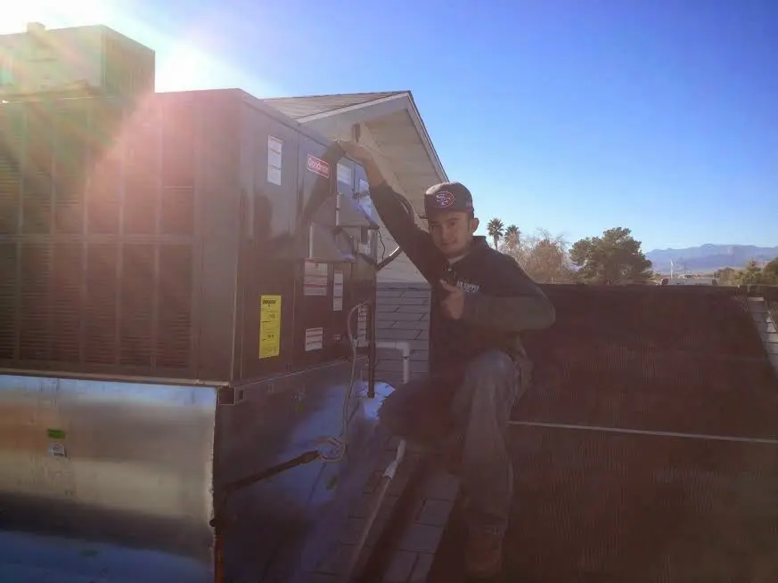 HVAC technician performing Heat Pump Repair on a rooftop unit in Rumford